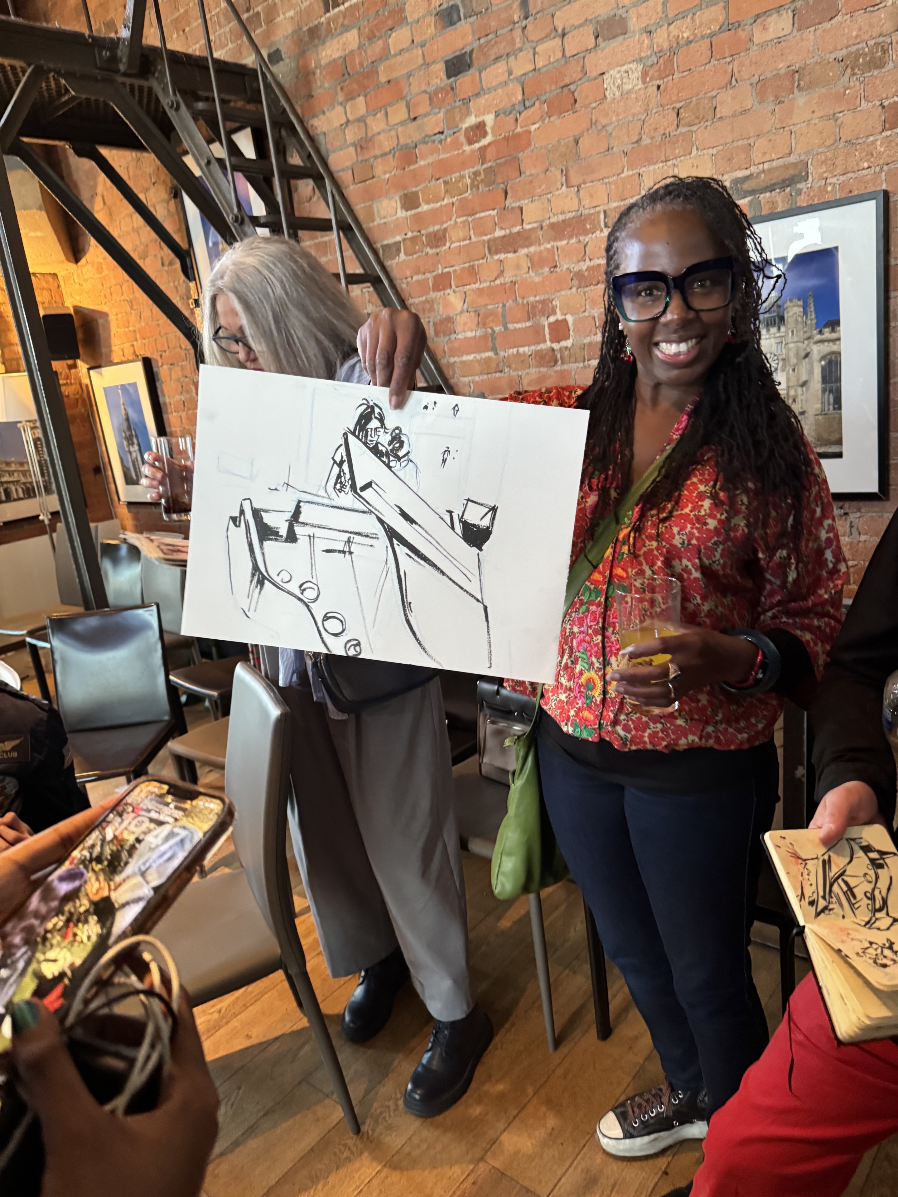 A smiling guest holding a line drawing made during the Clock Tower concert