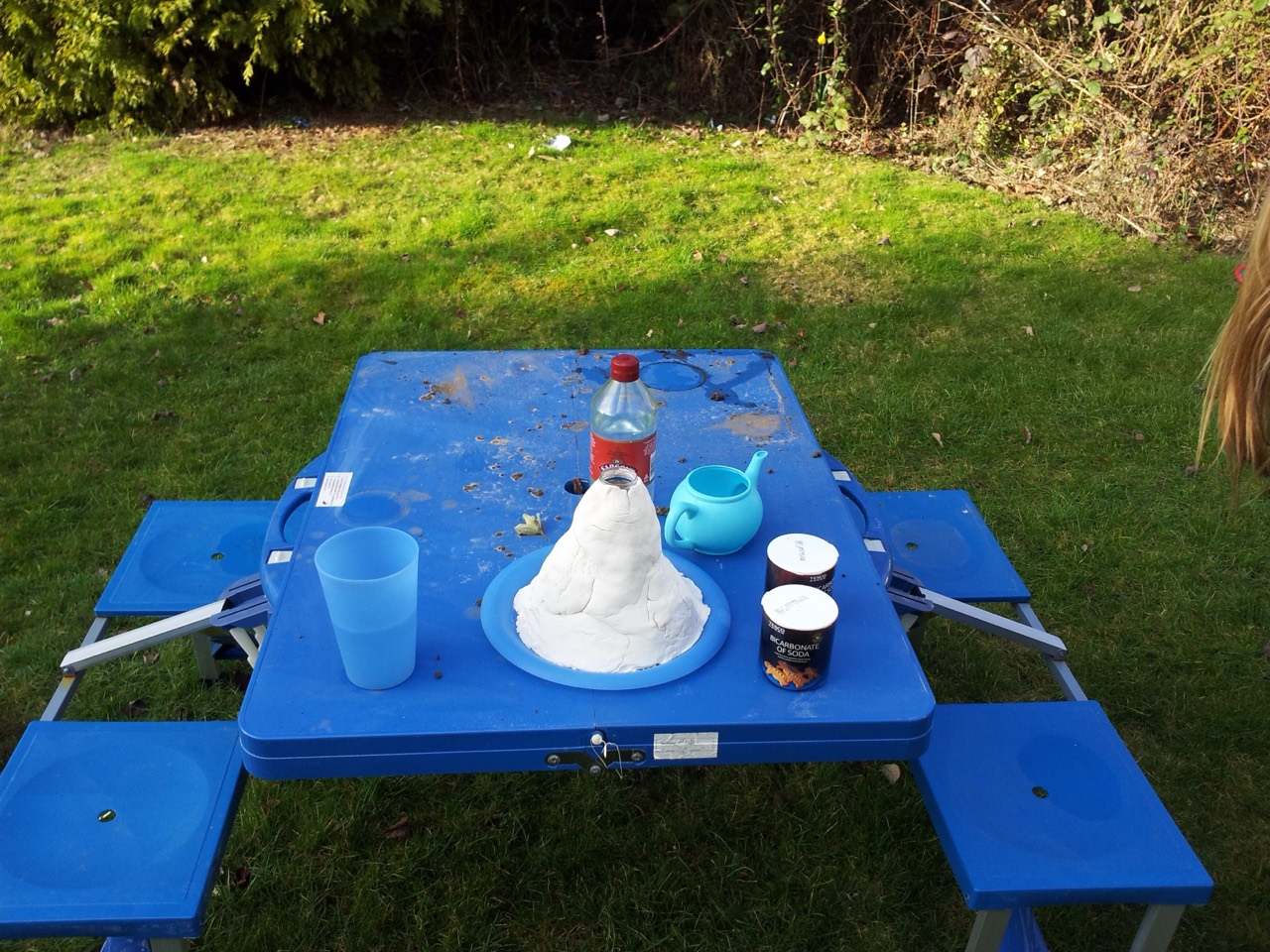 A homemade volcano experiment arranged on the garden picnic table.