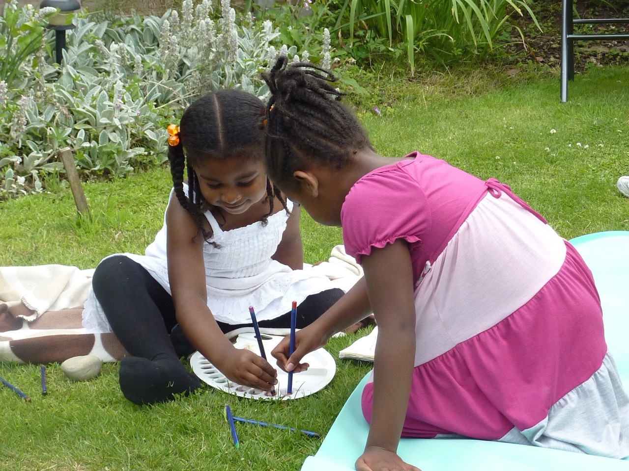 Two sisters painting together on the lawn.
