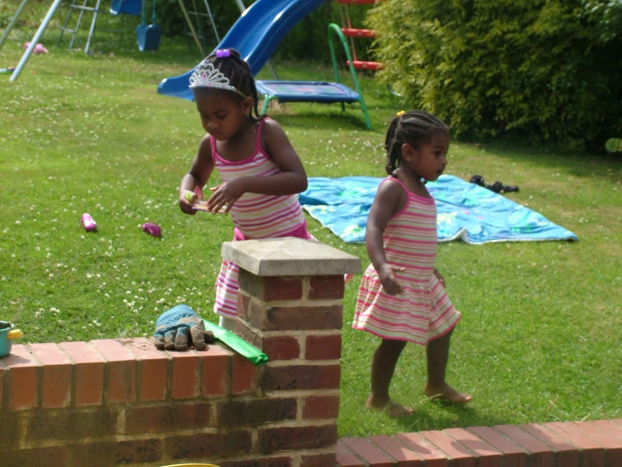 Two sisters playing outside in matching pink dresses.