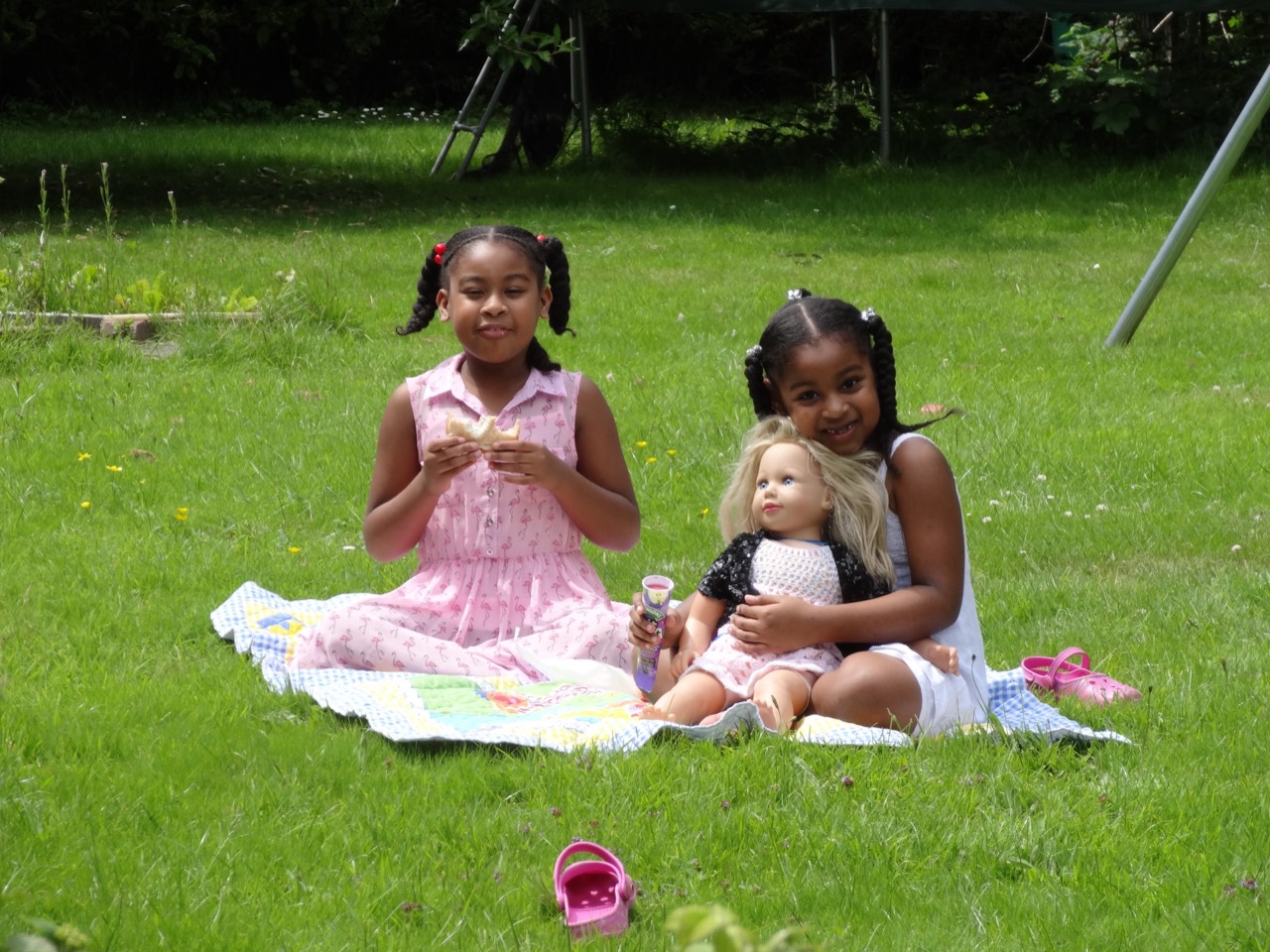 Two sisters having a garden picnic with a doll.