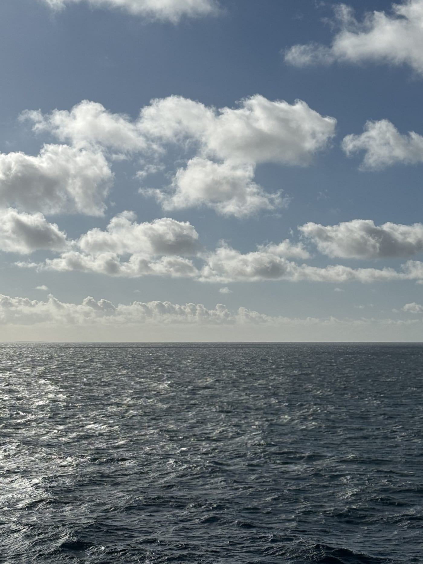 Open sea beneath bright clouds in a moody coastal landscape.